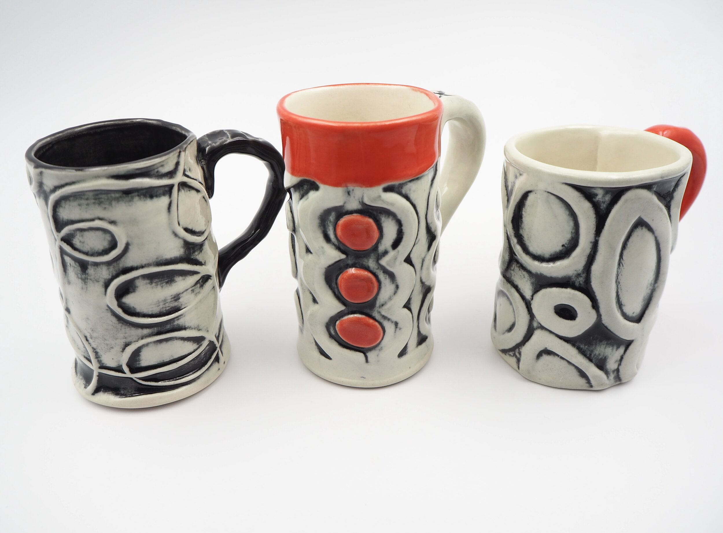 Three black and white (with red) mugs