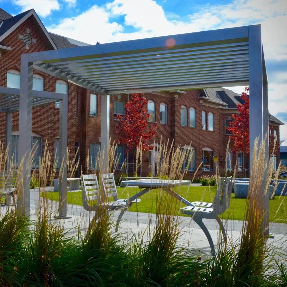 Architectural aluminum louvered pergola installed in a public park setting with integrated seating with table.