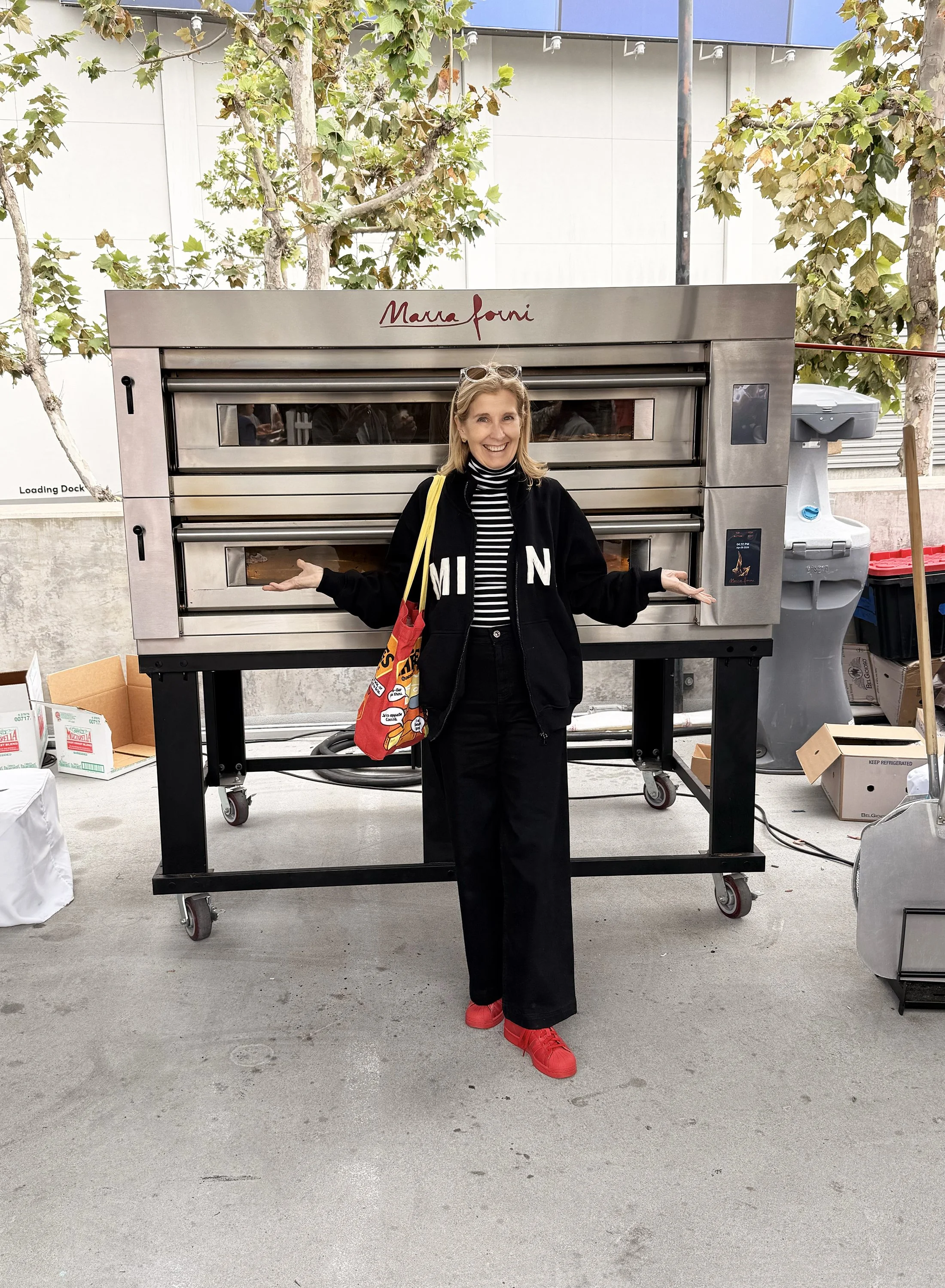 Natasha standing front and center with a huge pizza oven behind her at Pizza City Fest LA.