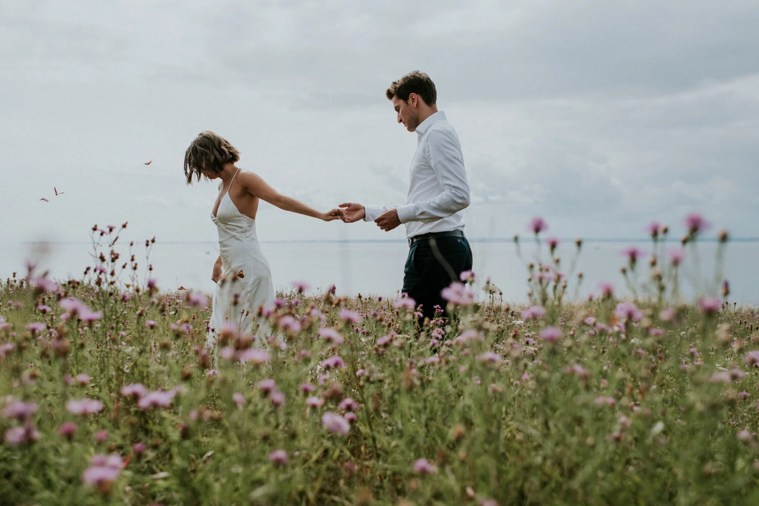 eloping couple walking in a meadow with butterflies on aeroe island in denmark