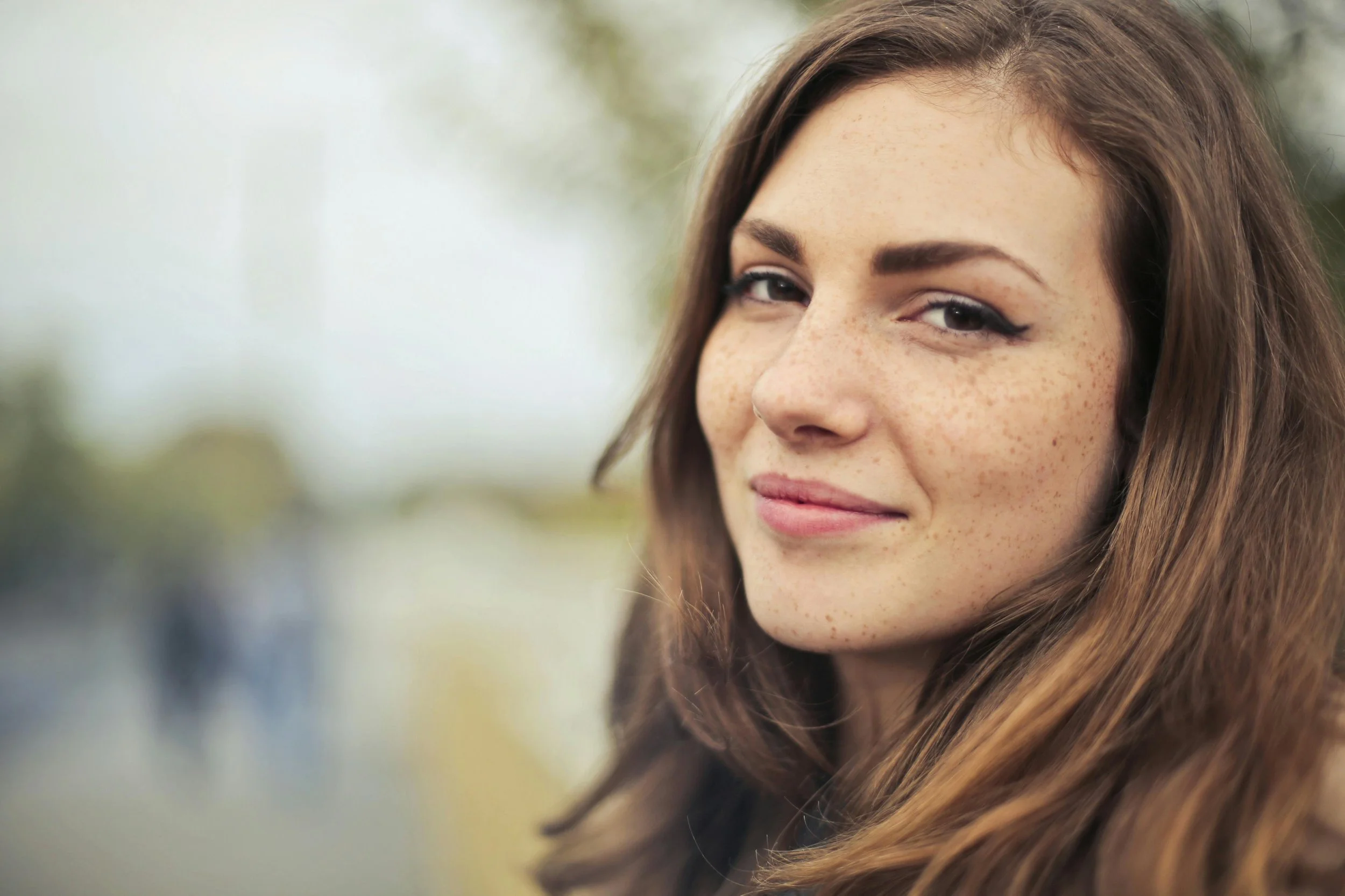 A woman with long brown hair and freckles smiling.