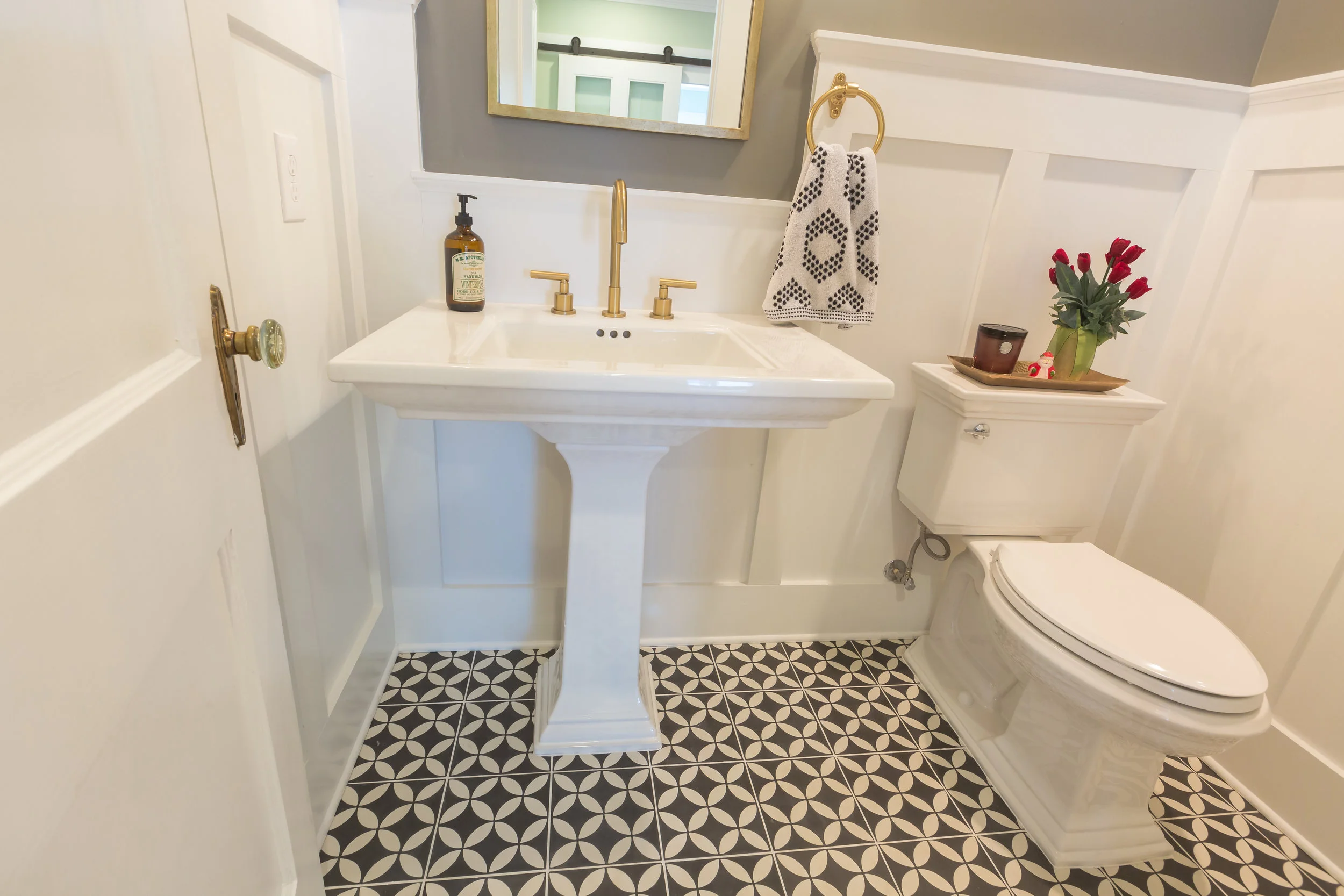 Vintage patterned tile makes this powder room seem larger. Perfectly paired with the pedestal sink and classic brass faucet.