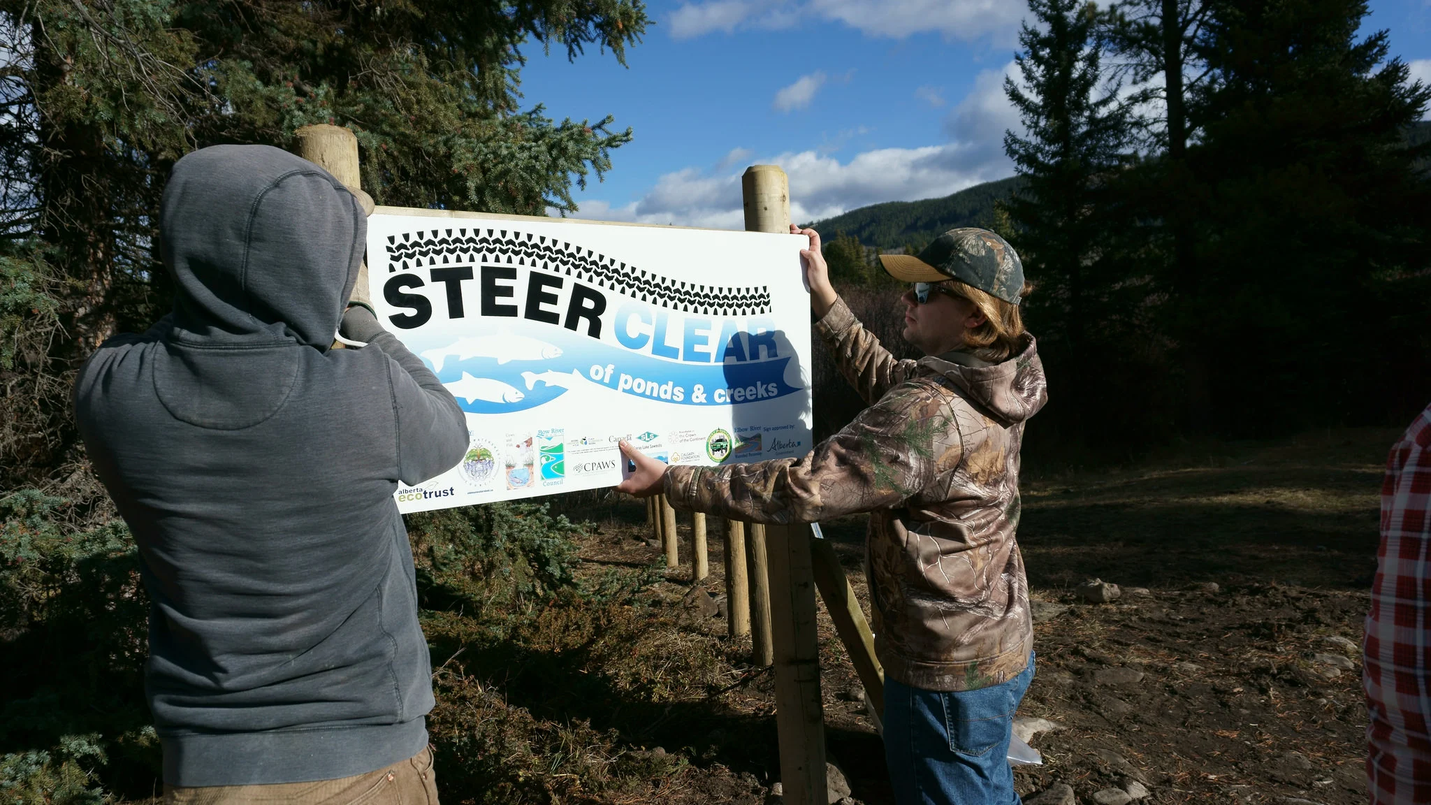 WLP Program Manager Cody Spencer (L) and volunteer Dylan Brassard put up one of 4 signs installed near the site. 2 are 'Steer Clear' signs and 2 explain the restoration activities.