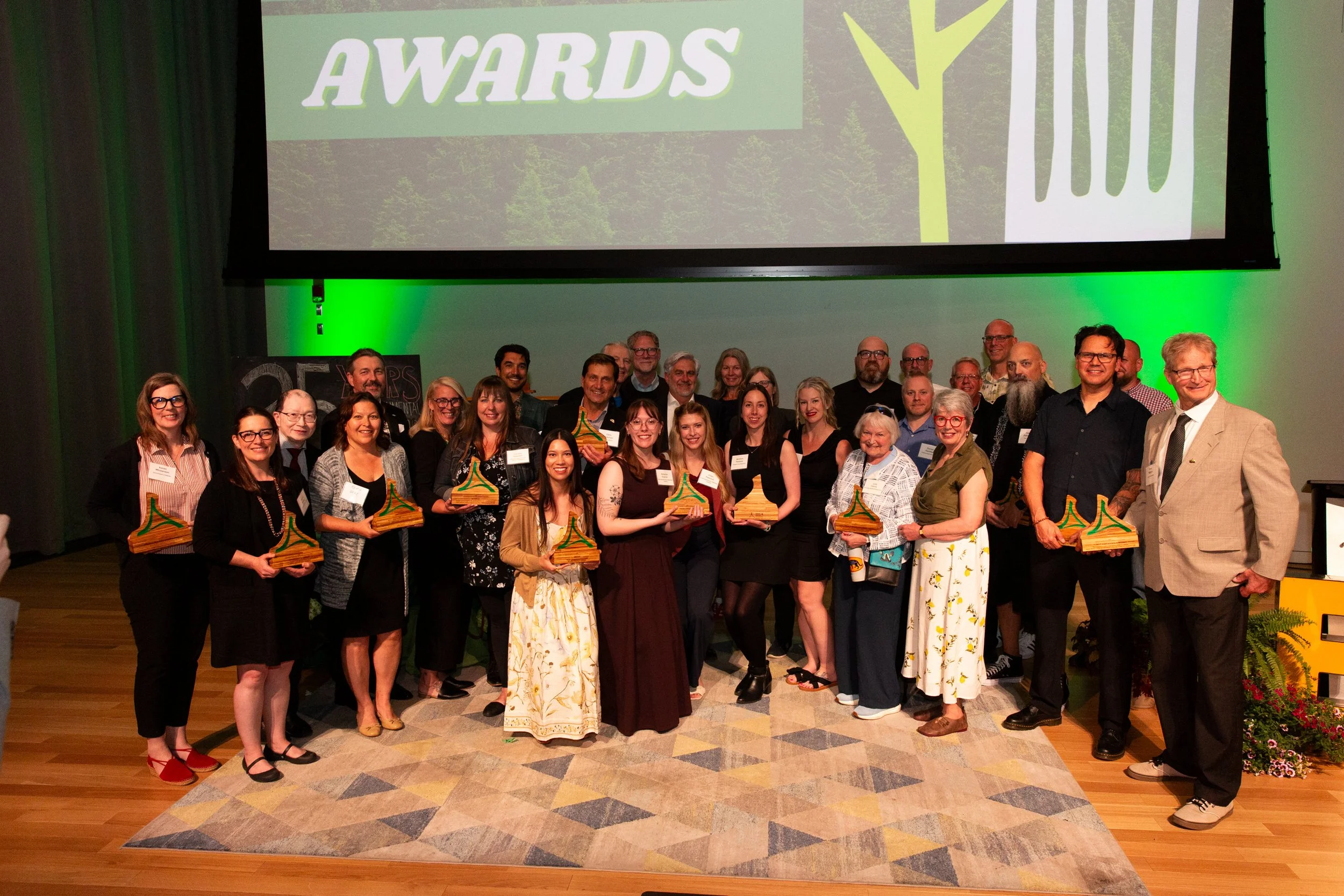 about 30 people holding awards standing on a stage