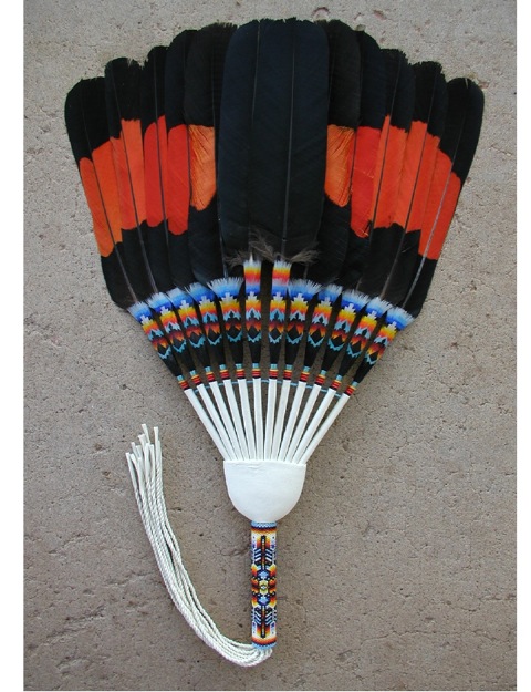 This style is a loose flat fan. The fan is strung together, so it opens up and close to fit into a gourd box. Sometimes there are no beads to hold these feathers together, and it drops like a drop fan. This would most likely be used by men. It can be used in dances, peyote ceremonies, and/or devotions