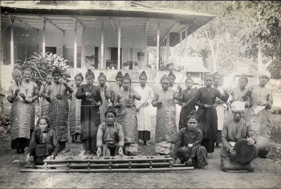 Sangirese priestesses of the Tabukan Kingdom pose with oli instrumentation - oli mouth harp, arbabu fiddle, sasaheng bamboo buzzers, and bangs flute. In the foreground is a set of kulintang gongs, and to the right is a tagonggong. in Tabukan, Sangihe Besar, 1927. Courtesy Leiden University Libraries Digital Collections.