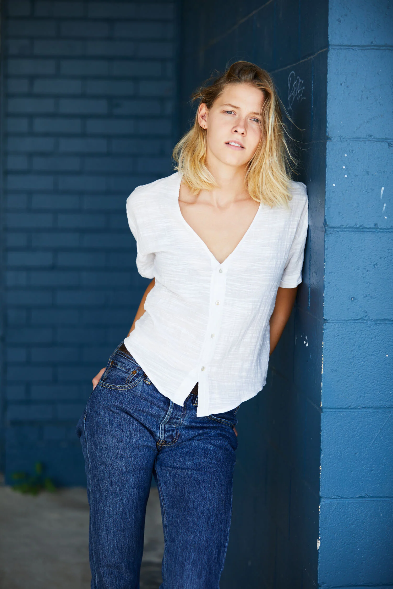 Portrait of young blond woman in front of blue brick wall
