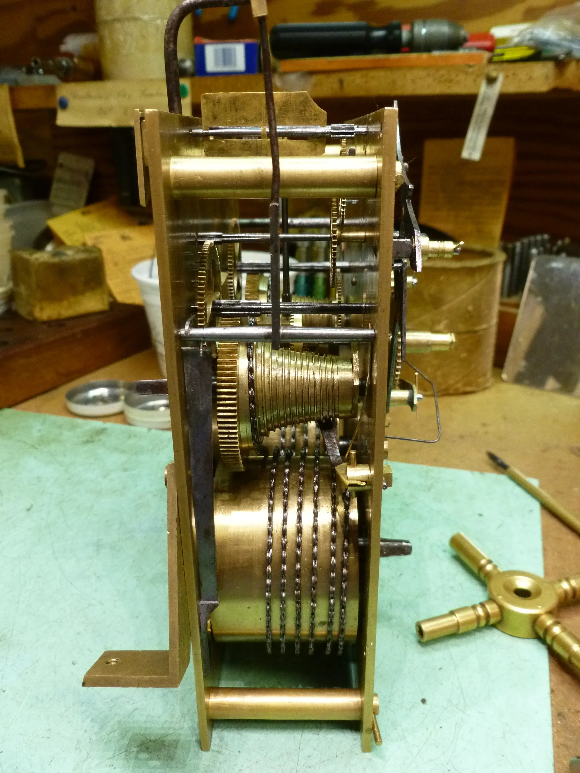 There is a large mainspring in the barrel on the bottom. To wind the clock, you wind the chain onto the cone in the middle of the movement. The theory behind the cone is that when the clock is nearing the end of the weak and the mainspring is running out of power, it provides the same amount of power to the mechanism using an adjusting ratio.