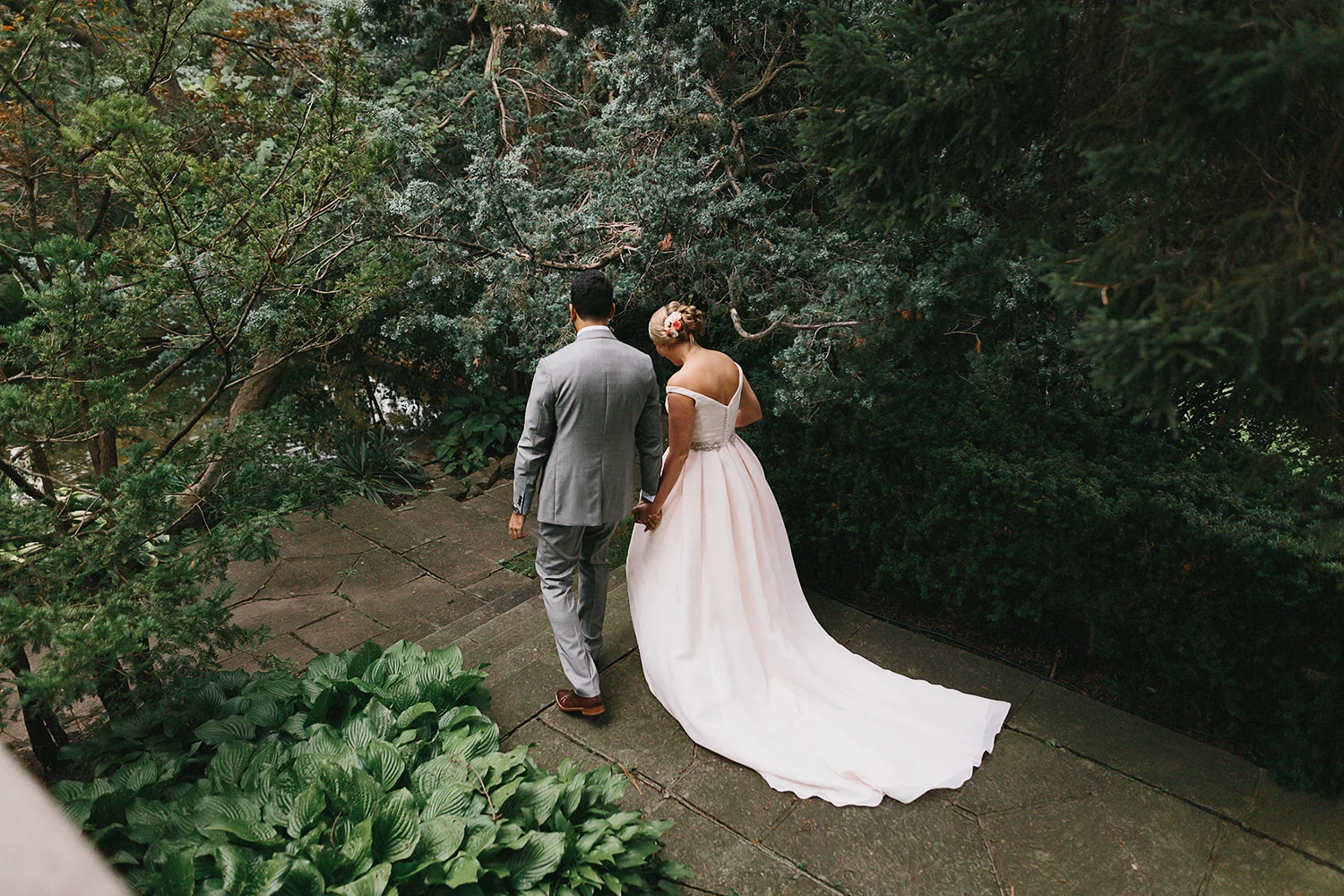 Graydon-Hall-Manor-Wedding-Toronto's-Best-Wedding-Photography-Ryanne-Hollies-Intimate-Small-Modern-Colourful-Wedding-candid-documentary-portraits-of-the-bride-and-groom-holding-hands-walking-through-forest-grounds.jpg