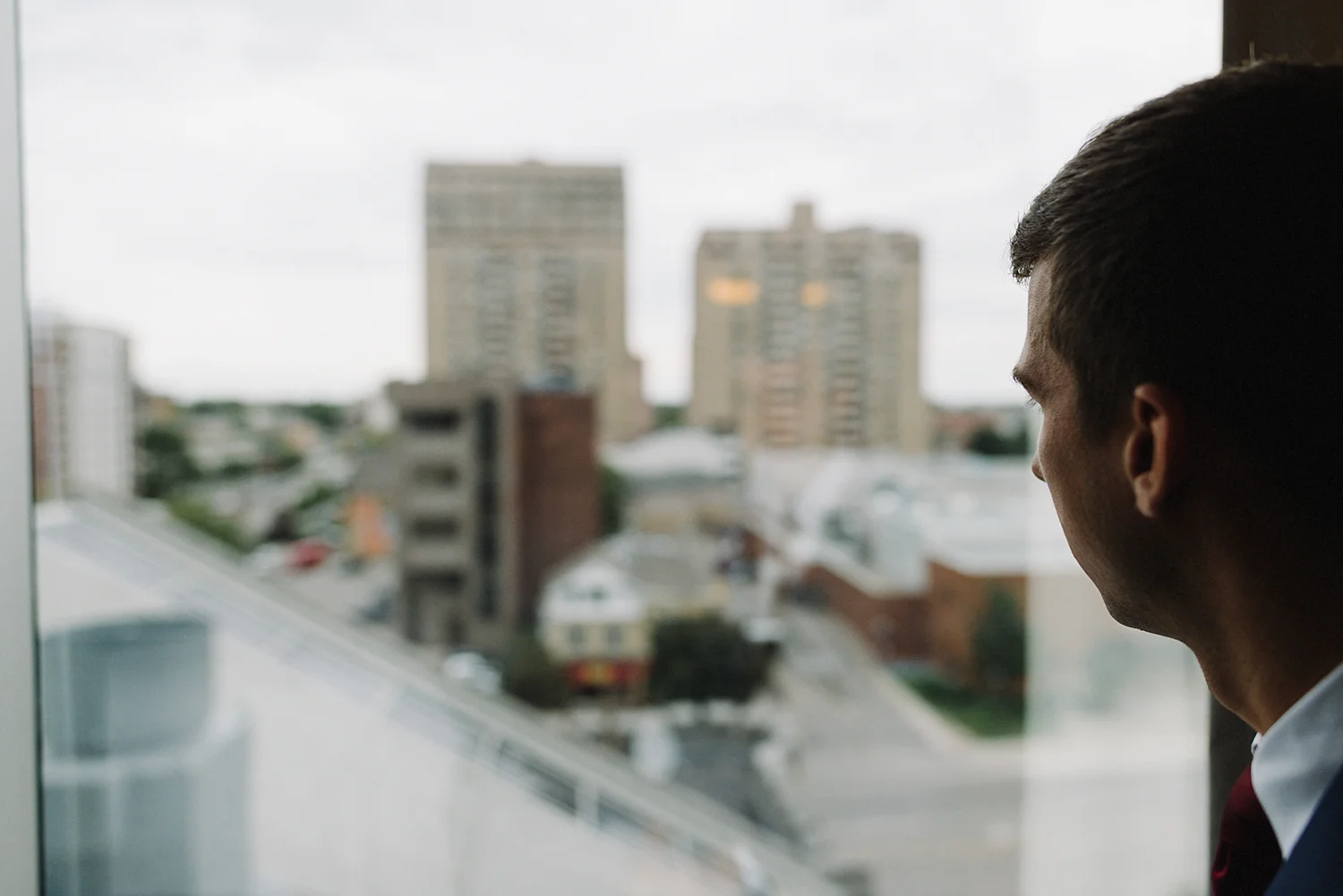 portrait-of-groom-lookig-out-window-at-hotel-getting-ready-in-london-ontario-wedding-inspiration.jpg