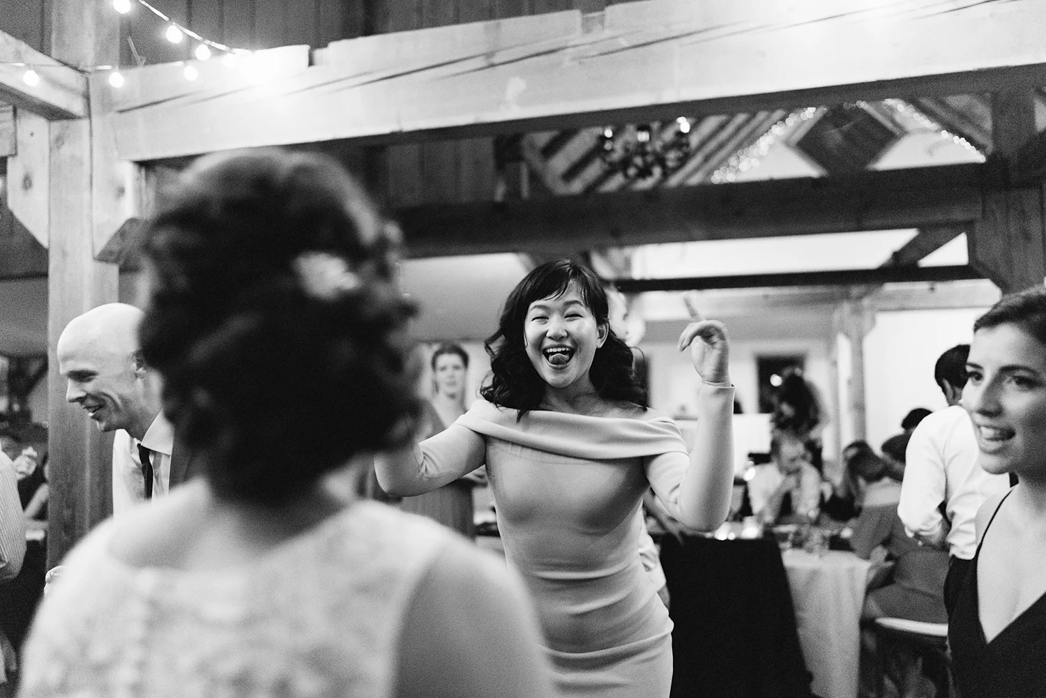 bw-candid-cute-dancing-in-barn-with-string-lights-toronto's-best-analog-documentary-wedding-photographers-candid-photography-london-ontario-wedding-inspiration.jpg