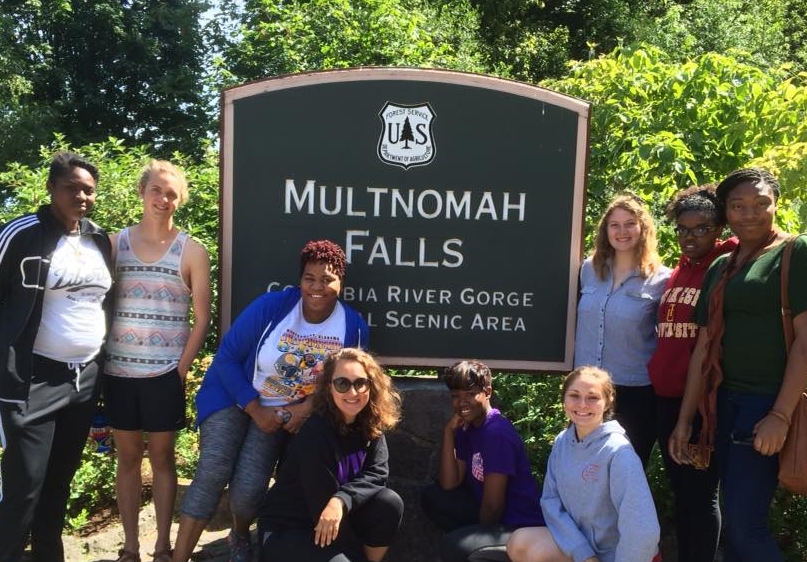 Ashley Tippit (standing directly to the right of the sign) and the rest of the QuadW Portland team on one of their Spiritual Retreat Fridays