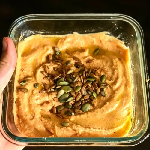 Pictured: Sun-dried tomato-roasted garlic hummus topped with spiced seeds.