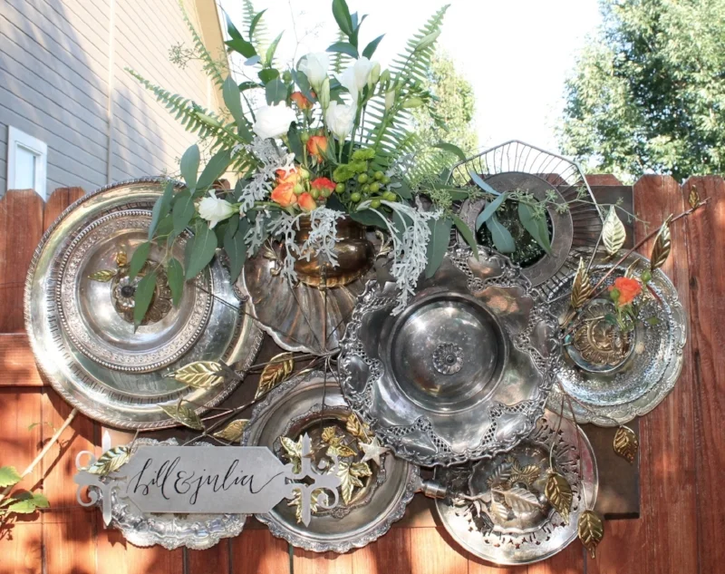 Backdrop for the wedding: platters, glass, brass, flowers and sign. Welding practice comes into play along with floral design.