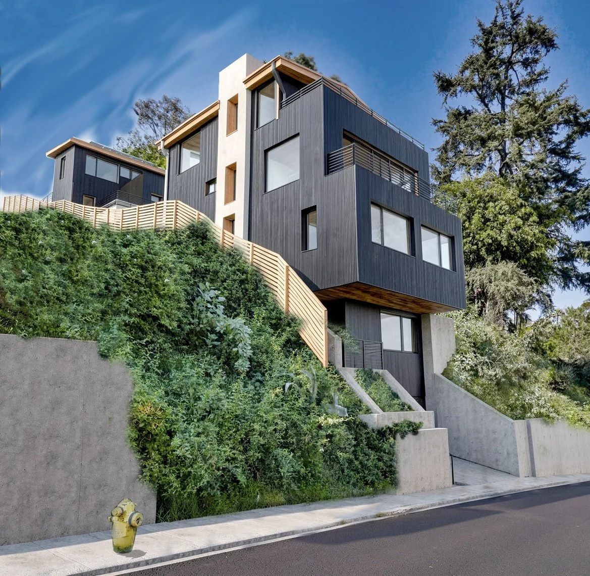 Modern multi-story house built into a hillside with black siding, large windows, and a wooden fence on a clear day.