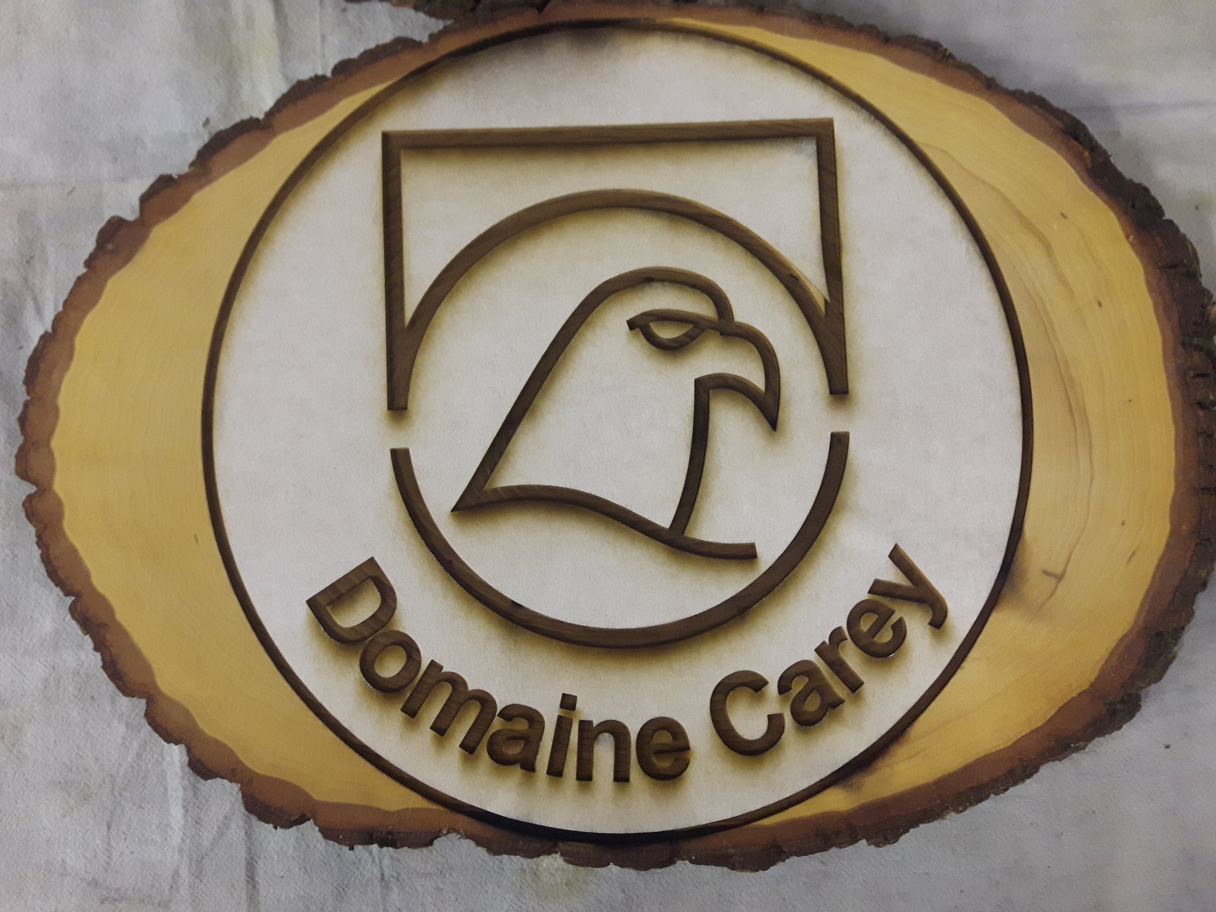 Enseigne en bois avec une bordure naturelle irrégulière, présentant un logo stylisé d'un aigle avec l'inscription 'Domaine Carey' réalisé par Systana Gavure Laser