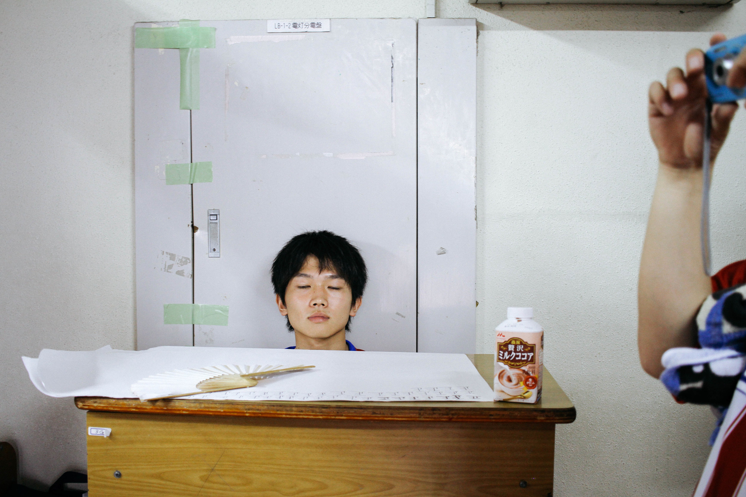 LONG SCHOOL DAYS KASHIWA MUNICIPAL HIGH SCHOOL, KASHIWA, JAPAN I can't look at this photo and not laugh. I took this at our school's annual Bunkasai festival and this boy was one of my previous students. The day was sweltering and he was sitting outside his homeroom working as a front desk person, checking people in to the game his class created. I caught him in this moment of pure exhaustion and it is now one of my favorite photos i've taken at school. 