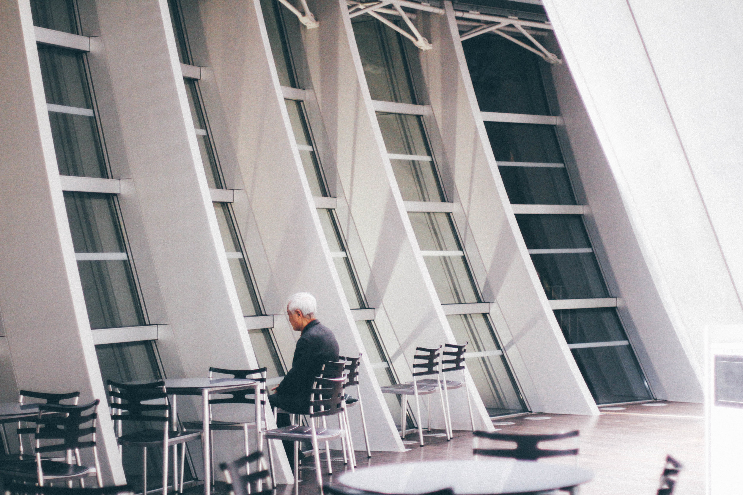 NO ONE NATIONAL ART CENTER, ROPPONGI, TOKYO I was walking through one of the best buildings in Tokyo, the National Art Center, when I saw this man and stopped dead in my tracks. What was he looking at? What was he thinking about? Something about it struck me. Maybe it was the way he was facing the window so directly. Or maybe it was the way his hair made a contrast with his dark coat. Or the weight I could almost see sitting on his shoulder. I don't know this man's story but his posture of loneliness and quietness is something I often see in Japan, and is a part of my daily prayers. Lord, you are here and now with these people. May they open up their eyes to see you and their hands to receive your blessings.