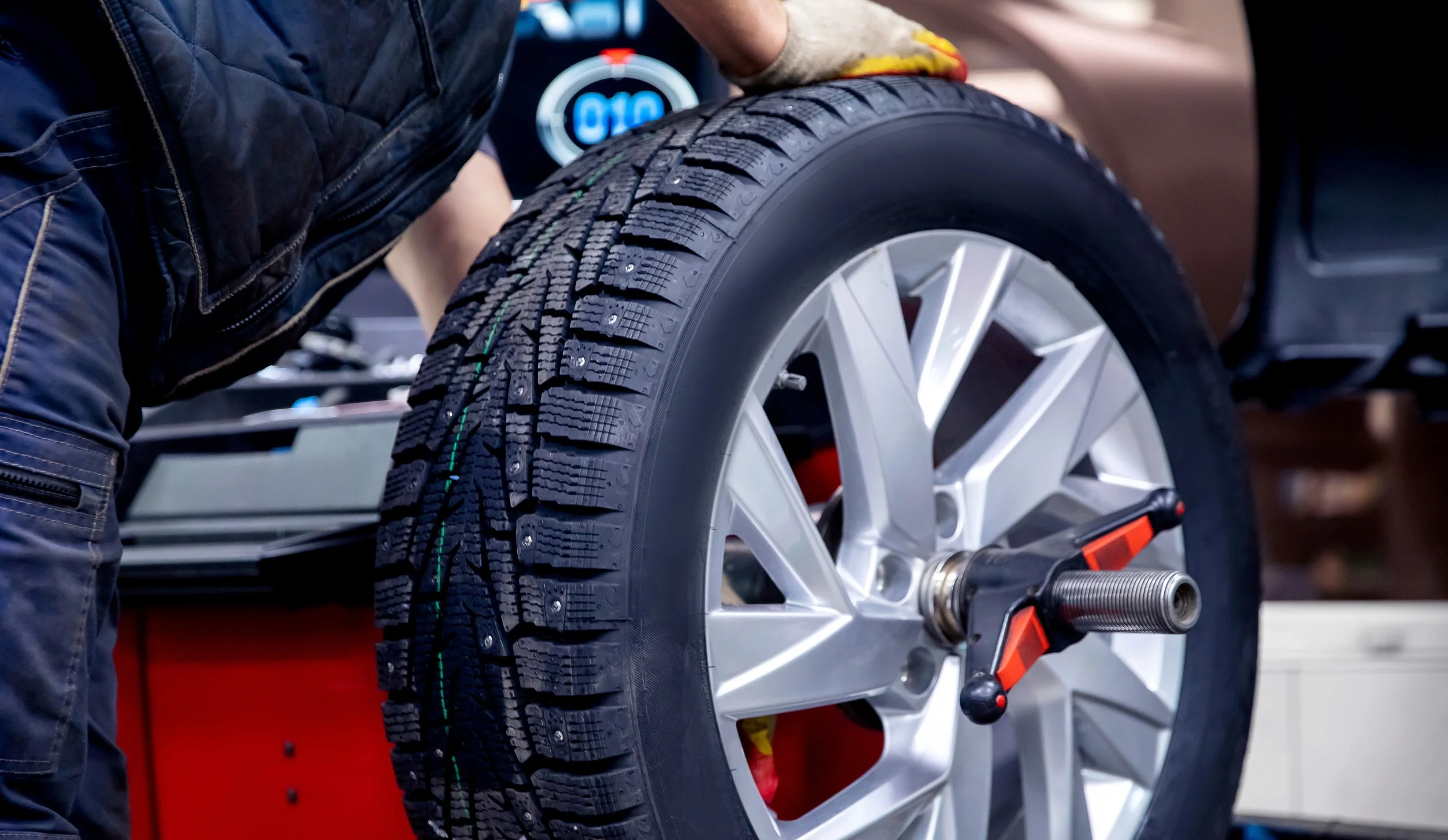 Person working on a car tire with a tire installation machine in a garage or workshop.