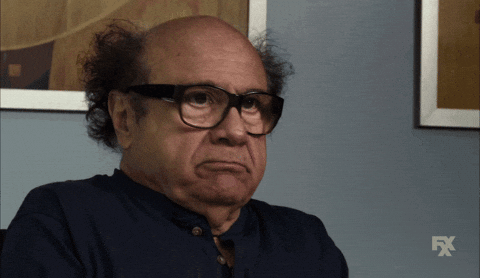 A man with glasses and curly hair, making an unhappy or displeased facial expression.
