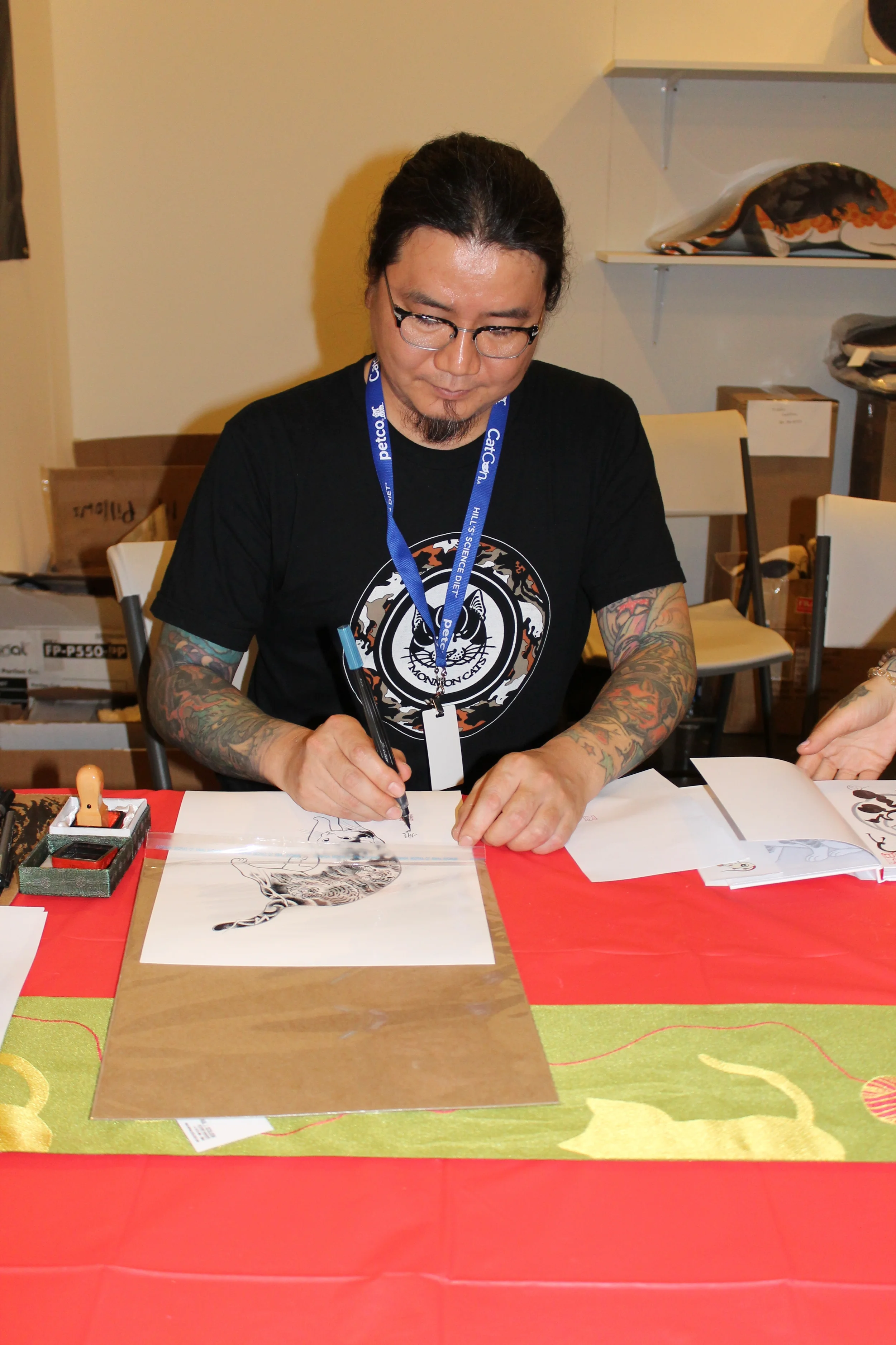 Sumi-E (Japanese brush painting) artist signs one of his creations for a customer