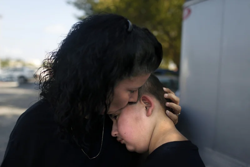 Maria Maldonado comforts her son Ethan Arbelo, 11, after ordering him to rest in the shade during a fundraiser hosted by the Latin American Motorcycle Association of Fort Myers. The fundraiser was held for Ethan’s health related expenses at Harley-Davidson on March 23, 2013 in Fort Myers, Fla. Maria, a single mom, often turned to her community for help because she struggled to maintain employment while attending to Ethan’s constant medical needs. 