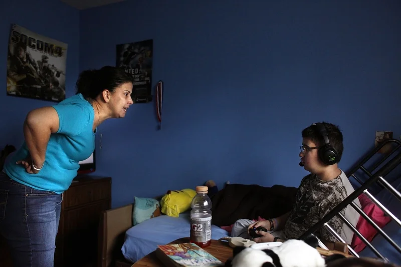While playing video games, Maria Maldonado yells at Ethan Arbelo, 12, for not putting more effort into using his left arm, which had begun to paralyze from swelling in his brain on December 2, 2013, in Lehigh Acres, Fla. As Ethan’s sole caregiver, M