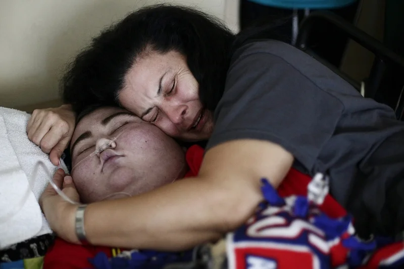 Maria Maldonado cries hugging Ethan Arbelo, 12, as he transitions into death on July, 3, 2014, in Lehigh Acres, Fla. “In those last minutes when you know your son is taking those last breaths, all you’re doing is praying for death for you too because you can’t imagine life without your baby,” Maria said. 
