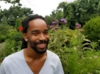 Gerard Miller is a Black nonbinary/agender queer native of Baltimore with roots in rural Maryland and North Carolina. They grew up surrounded by the Elders: both grandmothers and their siblings, 2 great- grandmothers, and a great-great grandmother, Mothers of the Church, and others in their wider community. Service of others, investment in self, and connection to Spirit through Nature and people have been foundational principles in their development. Gerard is interested in honoring and sustaining Ancestral legacies through movement, stories, crafts, and earthways; believing that our modes of survival can guide us to a prosperous future. Central to their vision is amplifying the voices and experiences of the most marginalized folx in society, reflecting their own African and Indigenous heritage and their queer identity. Working with performance, plant medicine, and storykeeping/-telling, they hope to integrate the parts of the 7-pointed star: the World Above, the World Beneath, the World Around Us, and the World Within.