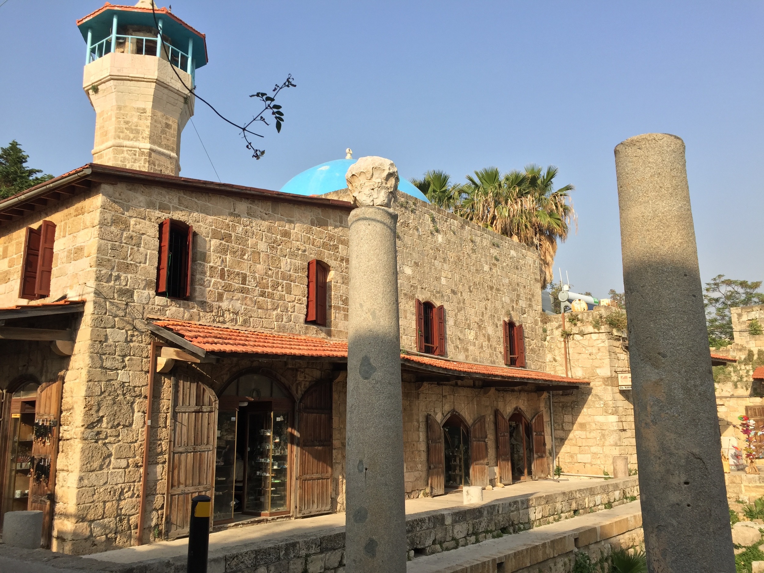 A tiny mosque stands next to ancient Roman pillars in Byblos