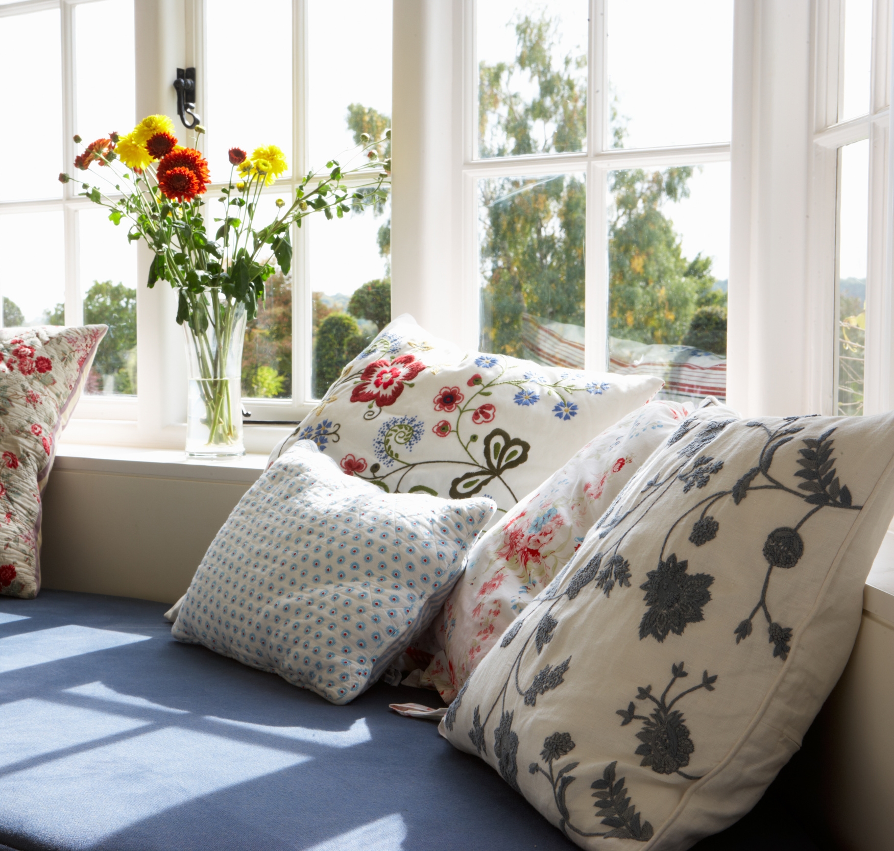 Embroidered Floral Pillows on Blue Seats in Window