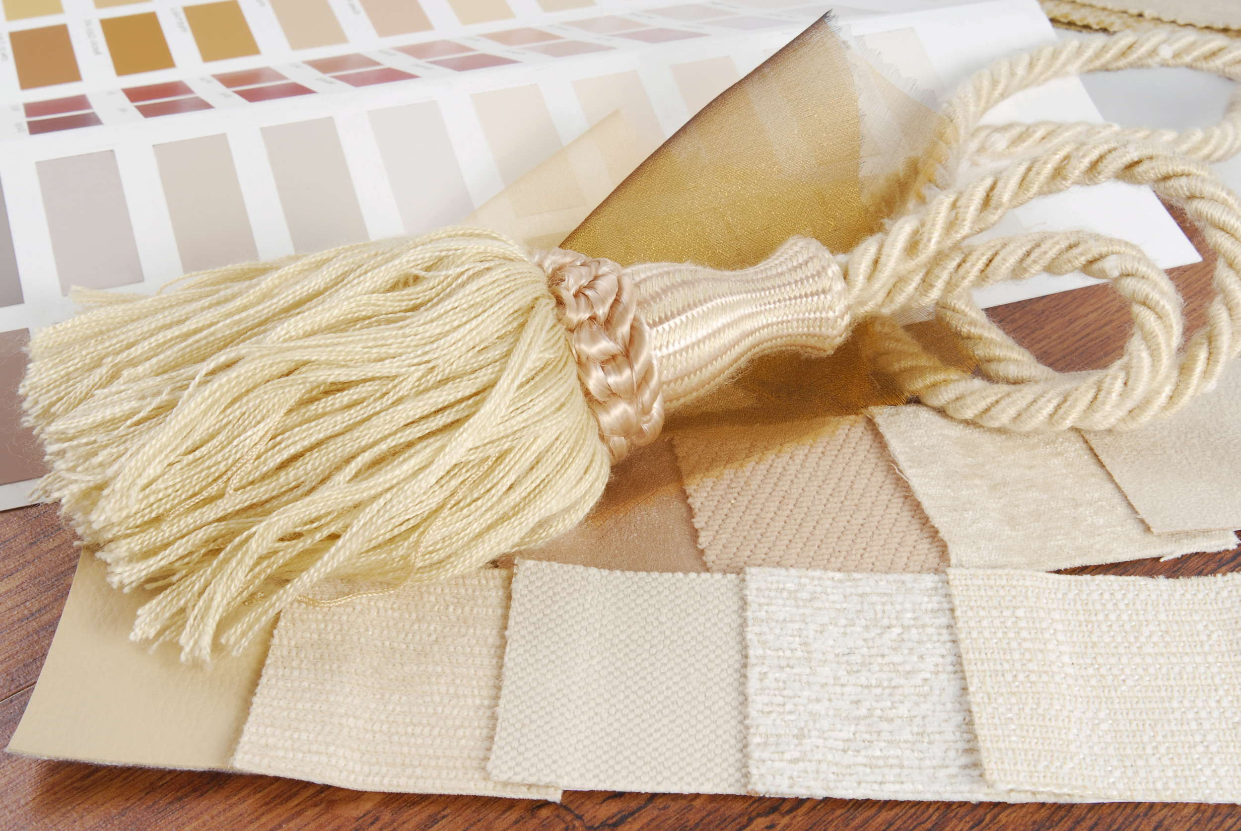 Cream Tassel with Varied Textures of Fabric Swatches and Warm Paint Chips
