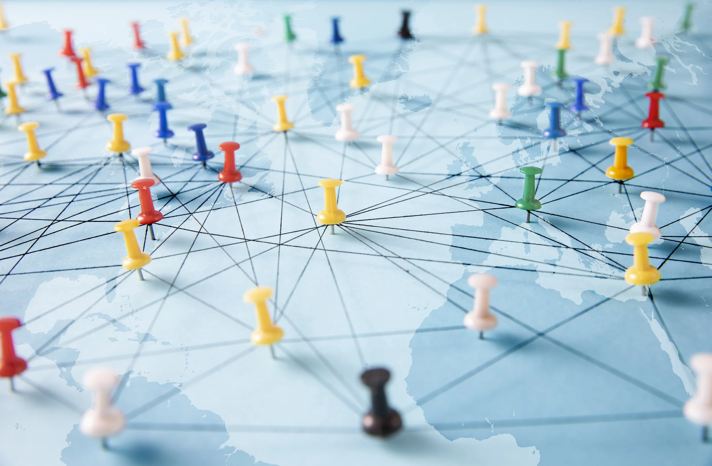 World map overlaid with a network of multicolored pushpins and connecting lines representing global connections.