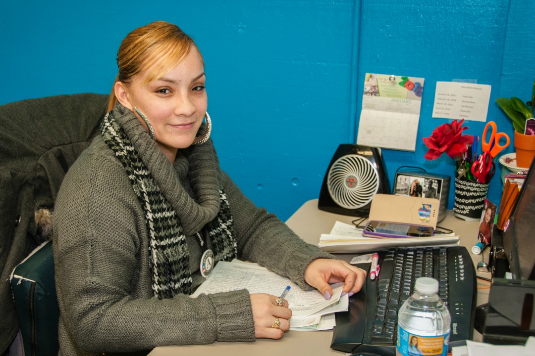 Ely sitting at her desk in cumac's pantry and referral office