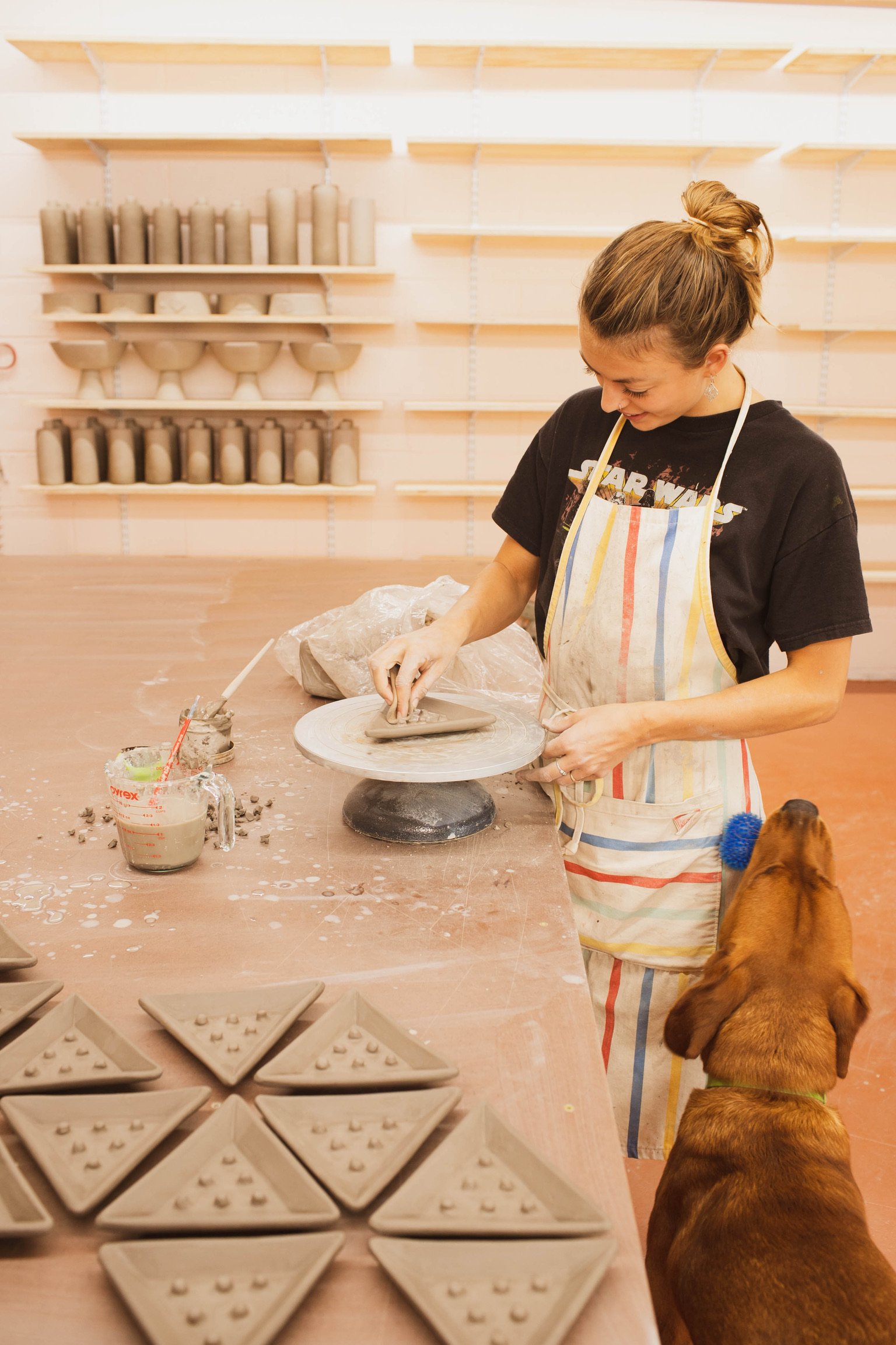  ceramic artist making pottery in pottery studio with shelves for pottery storage  
