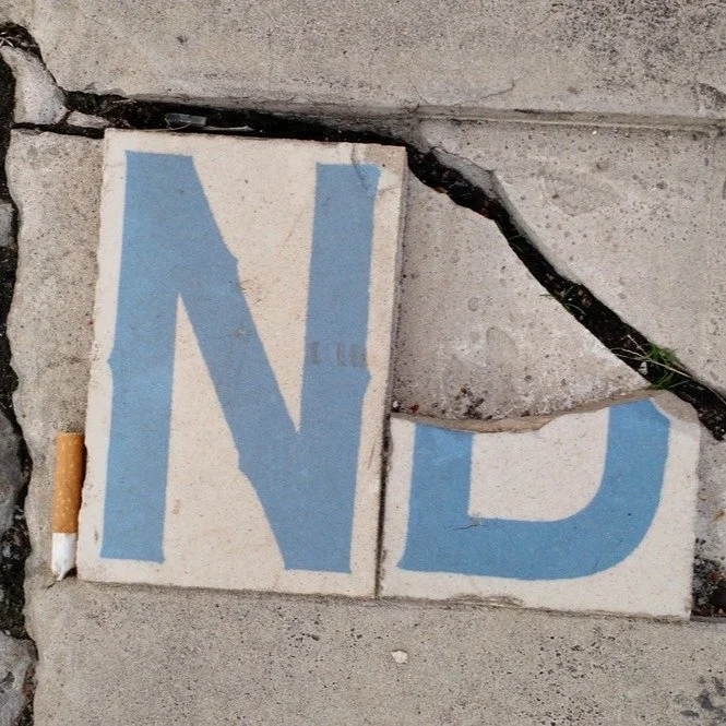 New Orleans street signs embedded in the ground are iconic blue-and-white ceramic tiles (4x6 inches) installed at intersection sidewalks beginning in the mid-1880s. Originally imported from Belgium, these tiles were designed for horse-drawn traffic, 