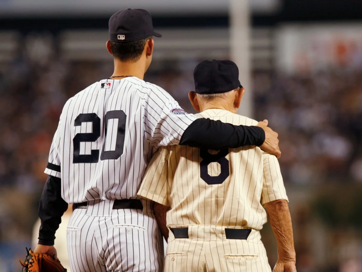 I love this picture. Jorge Posada with his arm around Yogi Berra. Even without the numbers, both famous Yankee catchers are unmistakable.