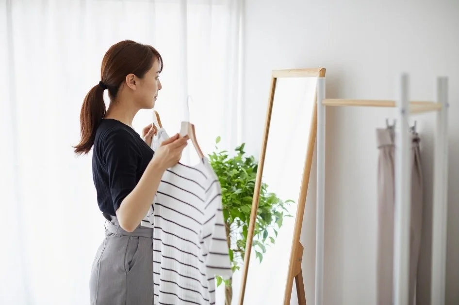 Woman choosing clothes, standing in front of a mirror.