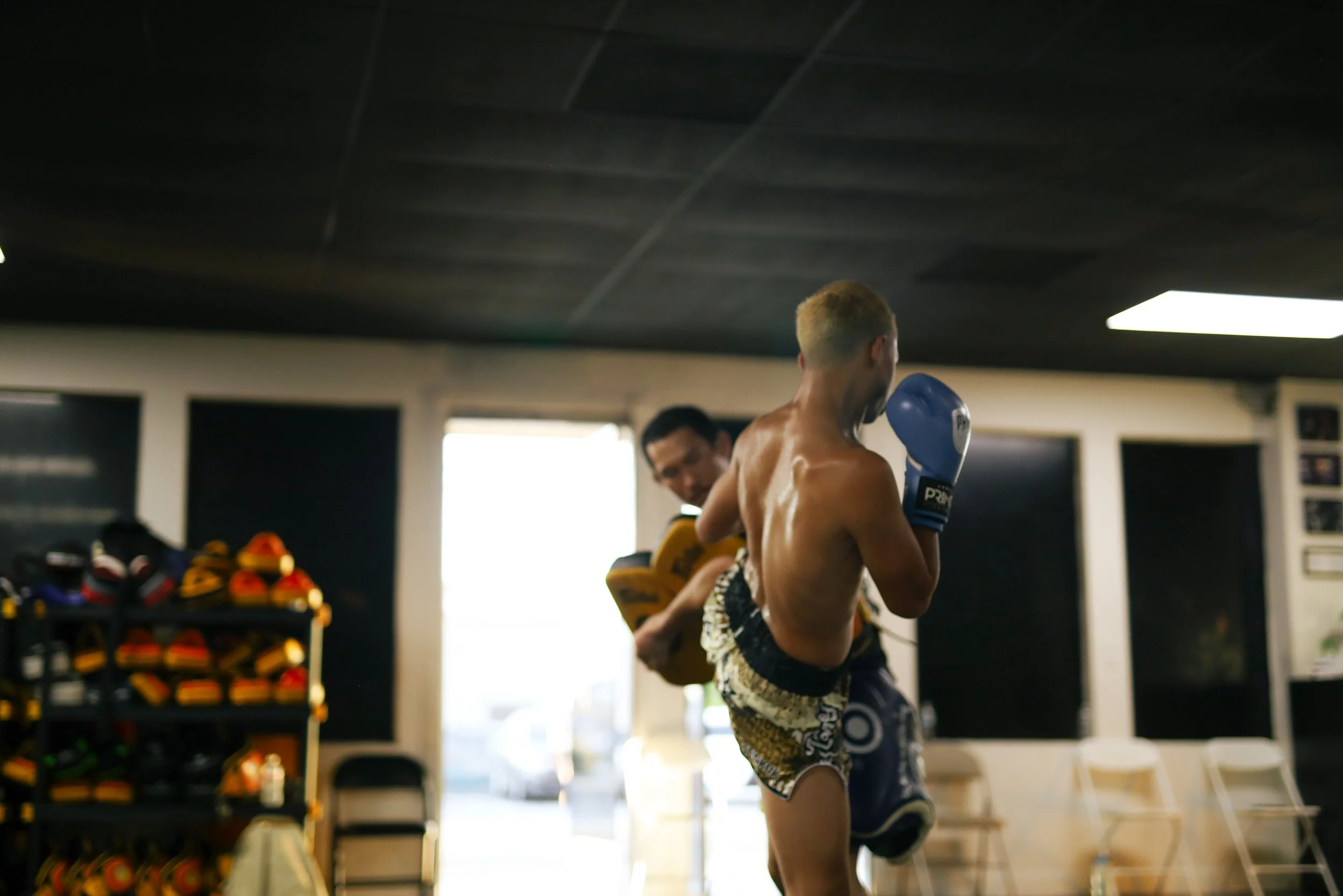 young muay thai fighter hitting pads