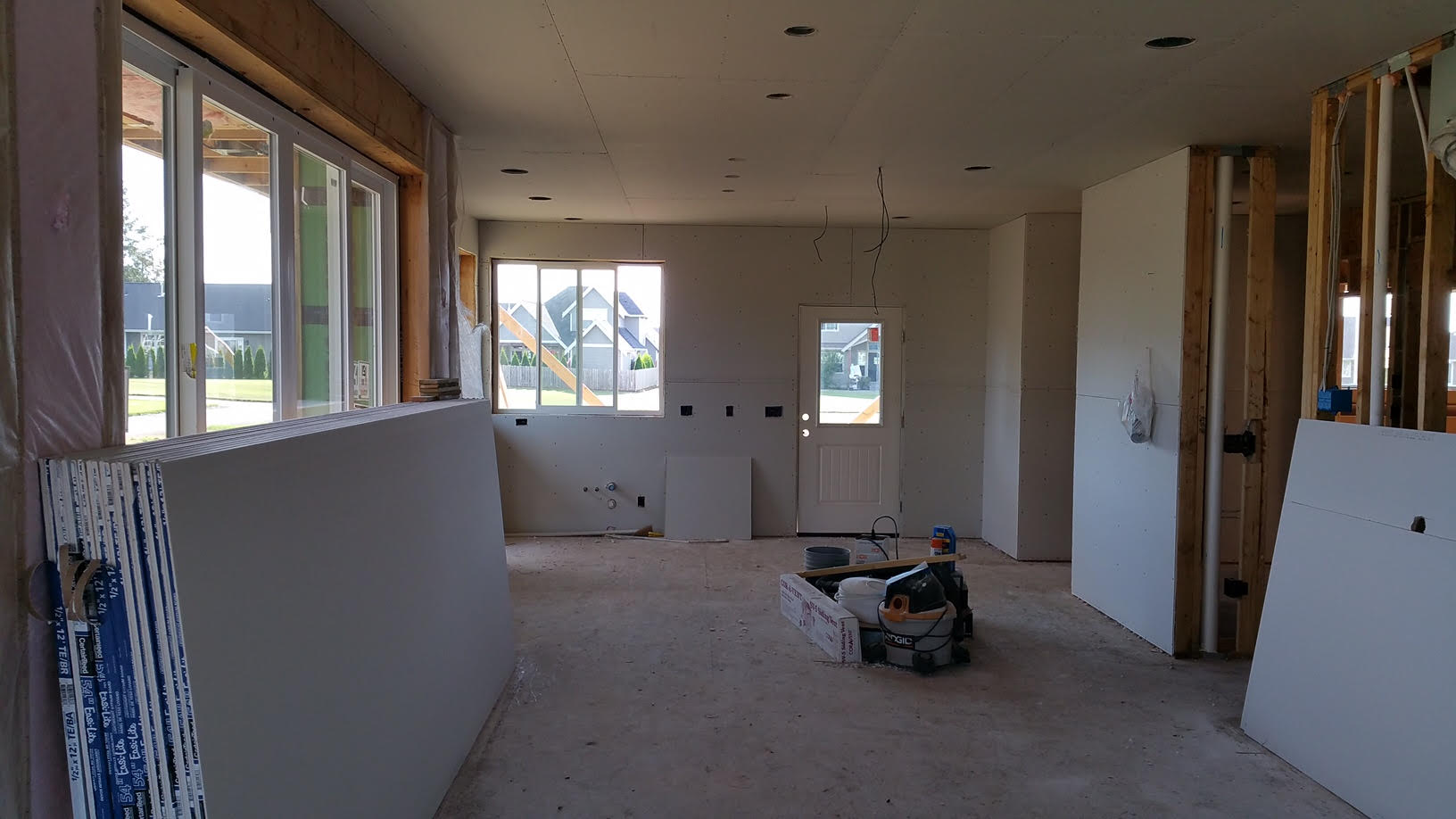 Standing in the living room, looking towards the dining room and kitchen. With interior walls close to being done, interior trim work, flooring and cabinets will be installed. 