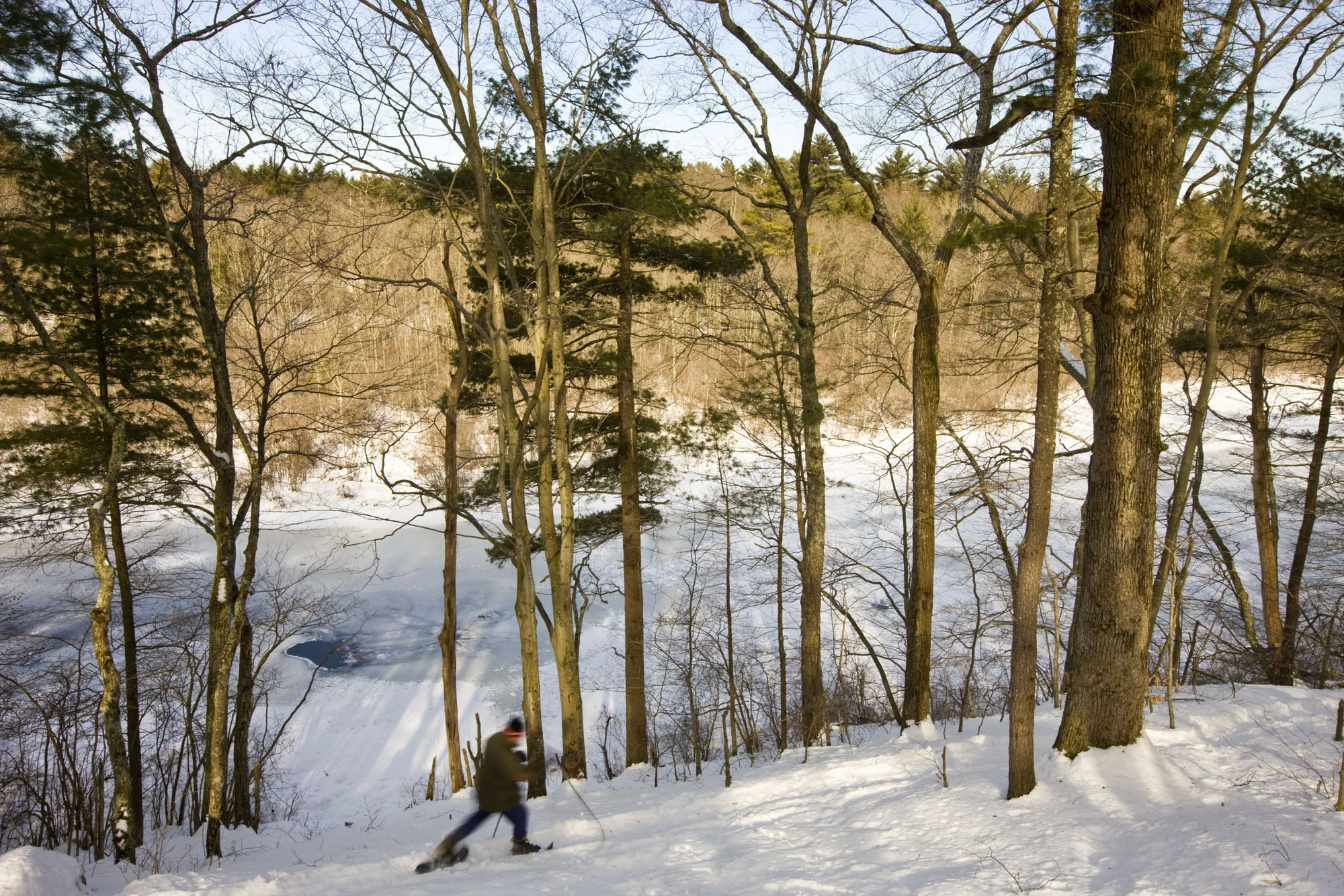 A man snowshoes next to the Indan Head River at the Tucker Preserve in Pembroke, Massachusetts. Wildlands Trust of Southeastern Massachusetts.