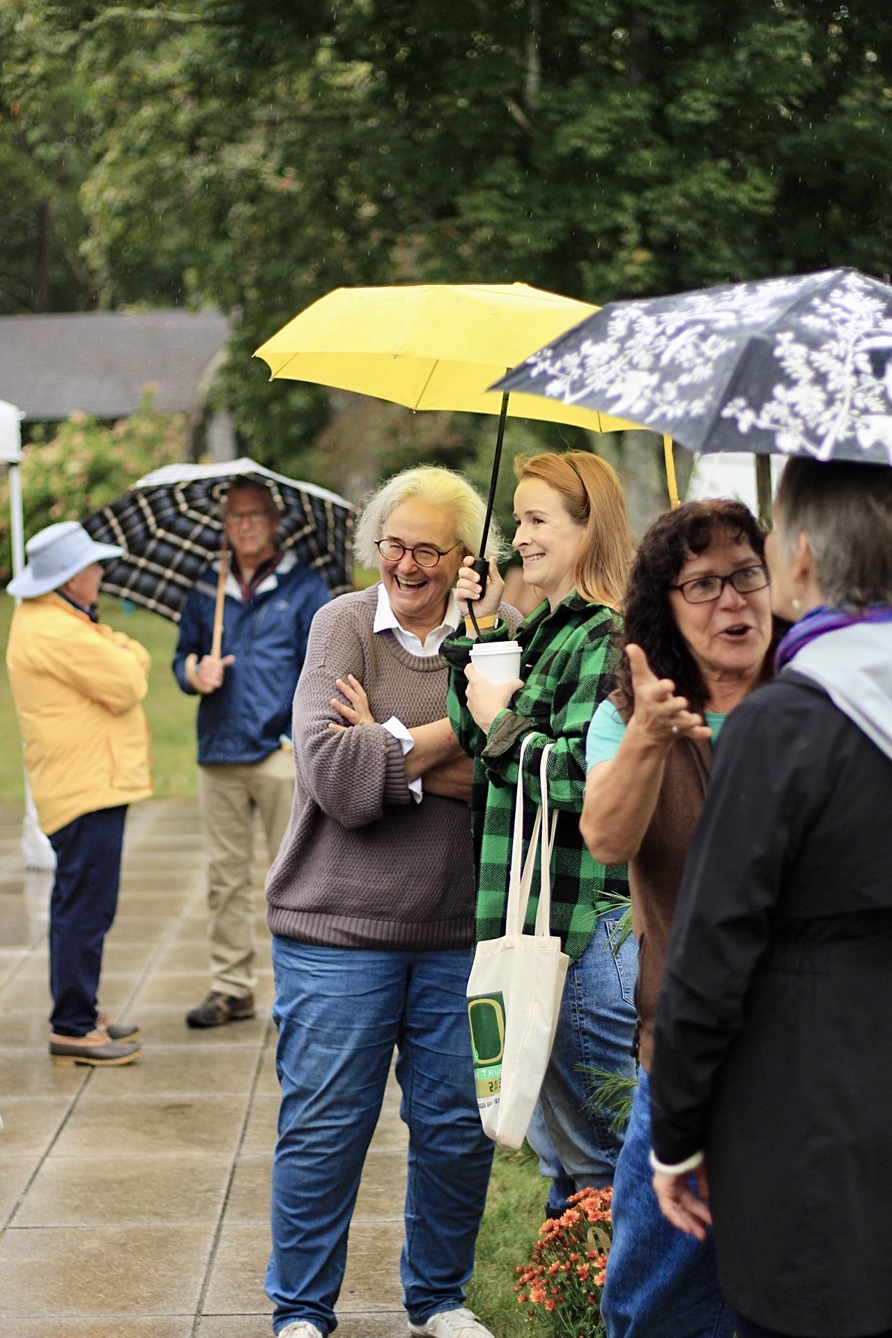 Celebration attendees share a laugh under an umbrella.