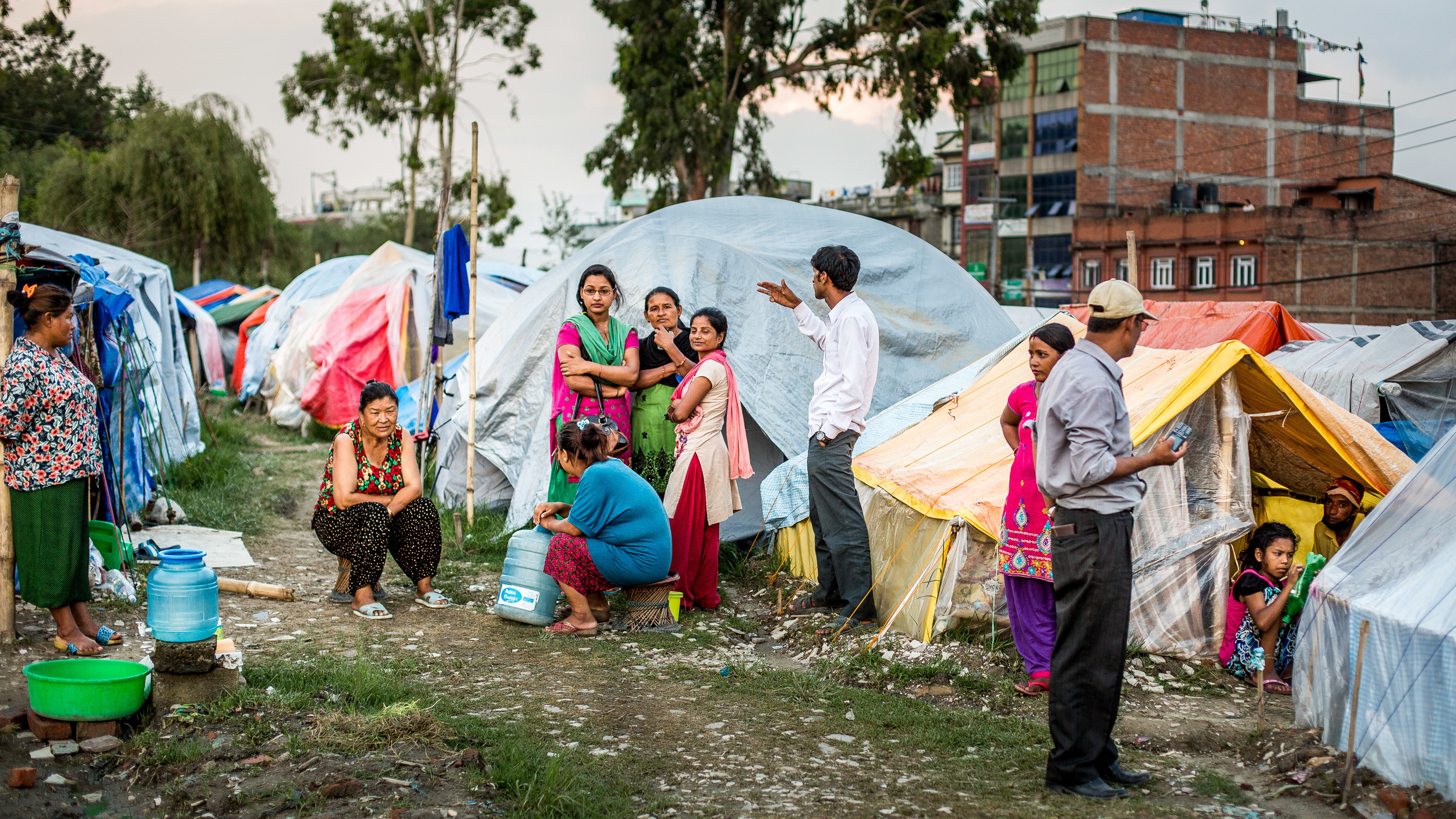 Camps where families still live under plastic.