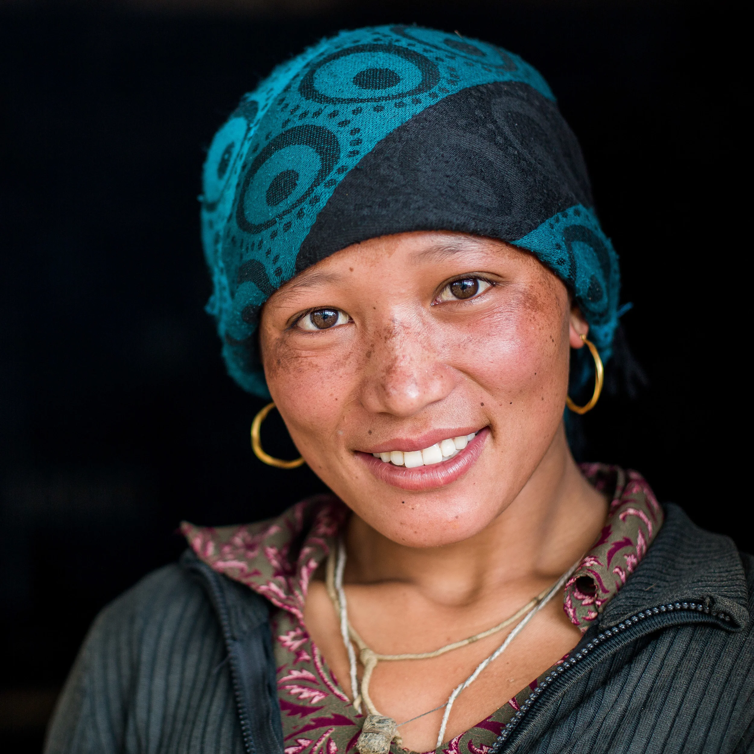 Woman with traditional clothing and earrings posing in her doorway. 