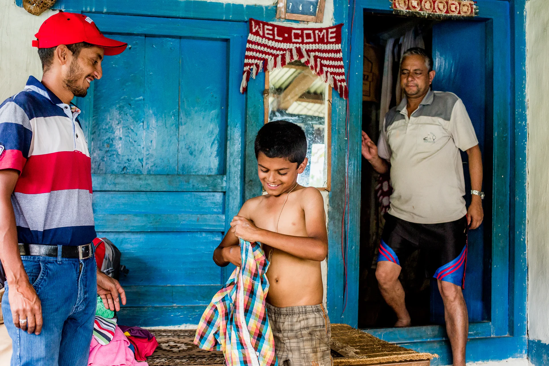 Boy from a poor family living nearby happy to try on his new shirt.