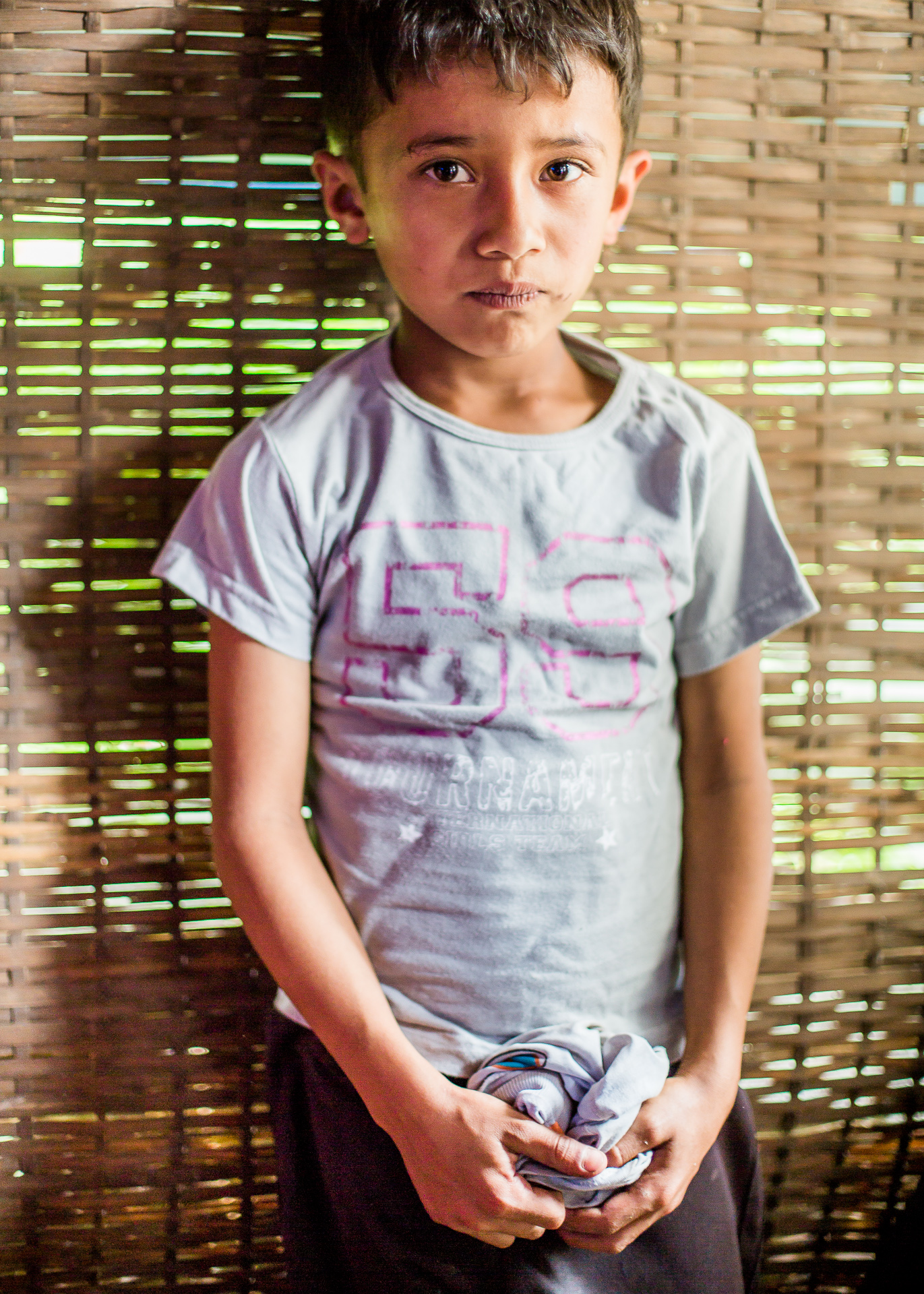 Posing with his new shirt in one of the temporary shelters made from bamboo with plastic sheeting for a roof. 