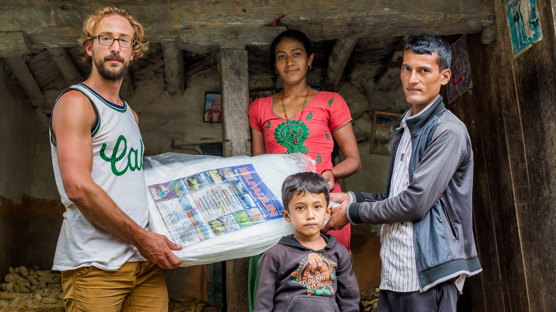 Handing over one of the plastic sheets to a teacher and his family. 