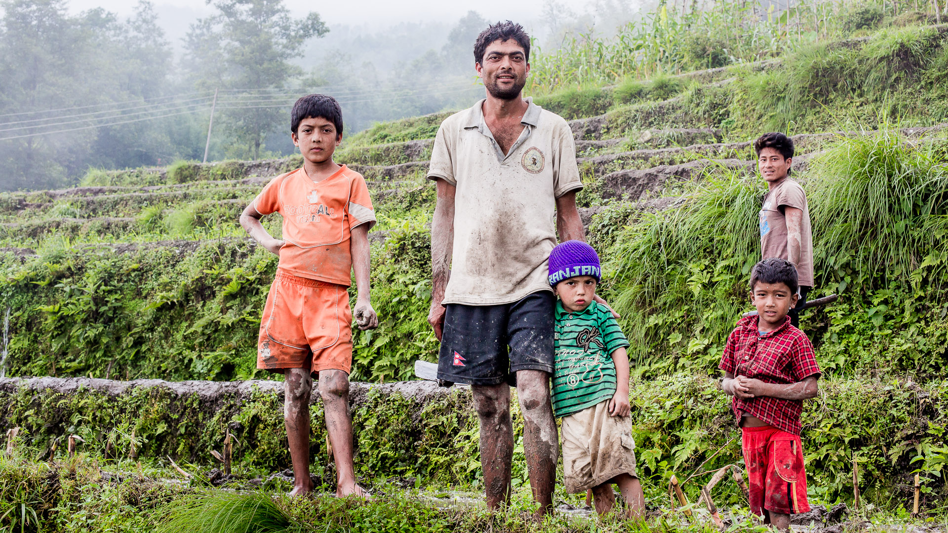 Dili Bastola posing with his children while working on his fields. Dili is starting a fish business by creating a fish pond just bit lower on the mountain. 