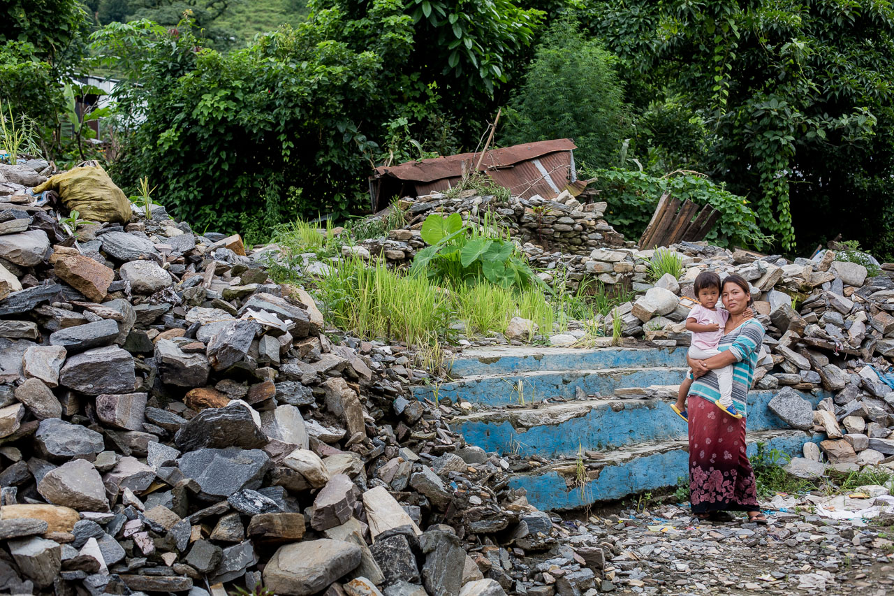 Pranjali Gurung in front of the steps to her family’s house. Now weeds have started to grow amongst the ruins.