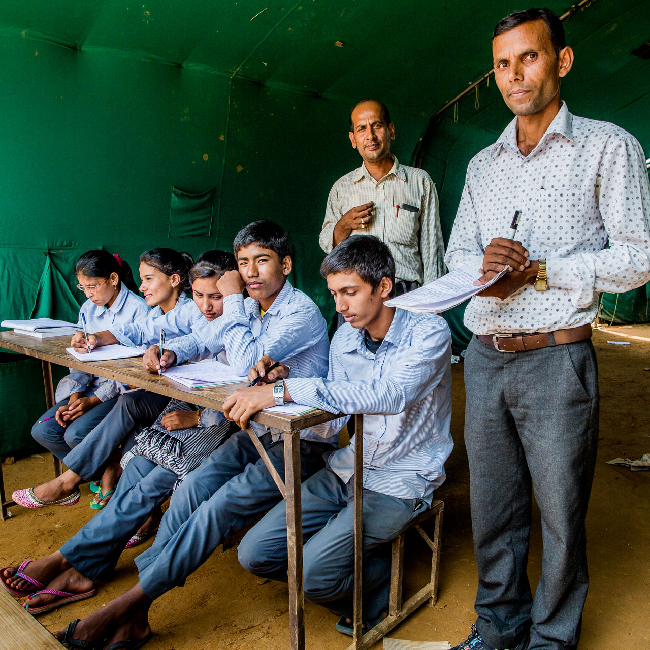 Principal, teacher and his class in their tent donated by the Indian Army.